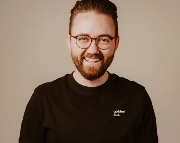 Mitarbeiter von goldencut.media in schwarzem Shirt vor neutralem Hintergrund